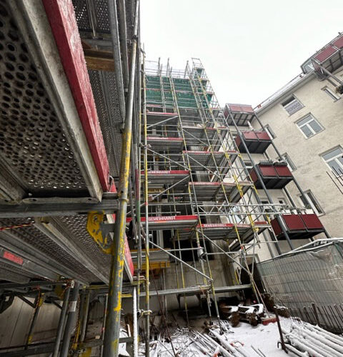 Gerüst an einem im Bau befindlichen Gebäude mit vielen Etagen, schneebedeckter Boden, winterlich.