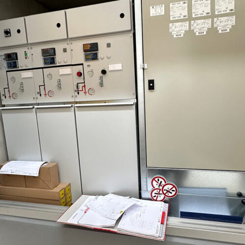 Ein elektrisches Schaltschrank mit Dokumenten und Kartons, Farbton: Beige und Weiß.