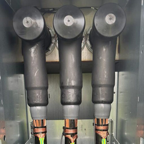 Drei schwarze Kabel in einem Kasten, teils offene Kupferdrähte sichtbar.