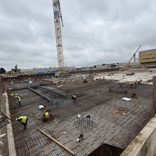 Eine Gruppe von Bauarbeitern arbeitet auf einer riesigen Baustelle mit viel Stahl.