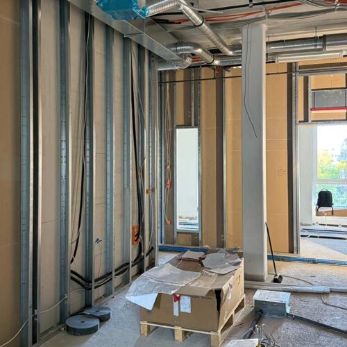 Eine Baustelle mit Kabeln, Kartons und einem Fenster im Hintergrund.