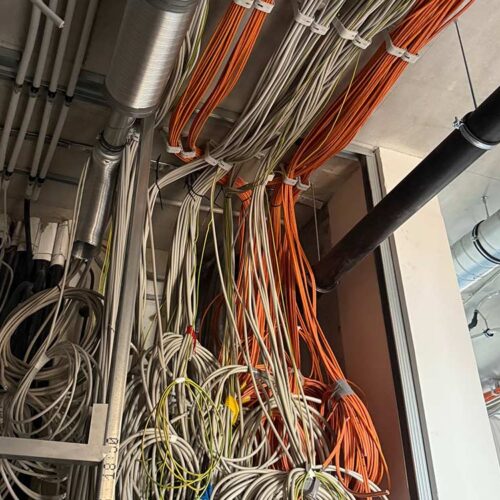 Ein Gewirr aus weißen und orangefarbenen Kabeln in einem technischen Raum