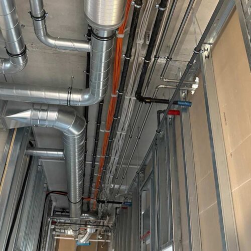 Lüftungsrohre und Kabel verlaufen an der Decke eines unfertigen Gebäudes.