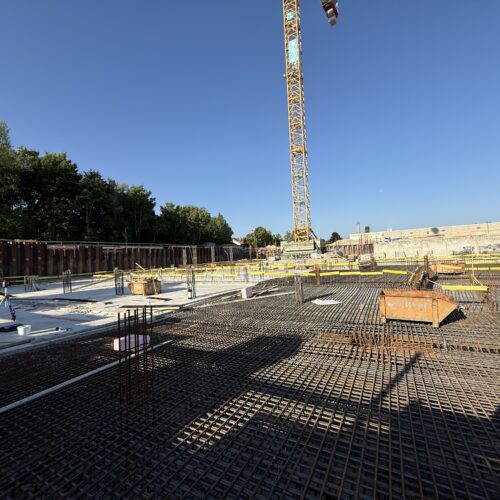 Bauarbeiten auf einer Baustelle mit einem Kran und Betonfundament unter klarem Himmel