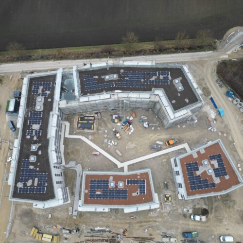 Luftaufnahme von einer großen Baustelle mit Gebäuden und Solarpanels auf den Dächern