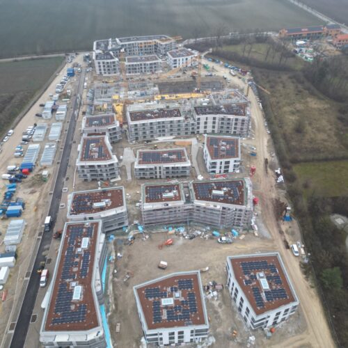 Mehrere moderne Wohngebäude mit Flachdächern und vielen Baustellenfahrzeugen