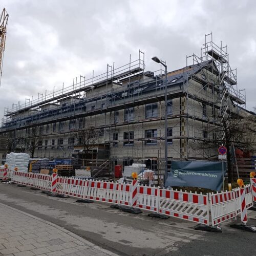 Eine  große  Baustelle  mit  einem  teilweise  eingerüsteten  Gebäude  und  gelbem  Kran