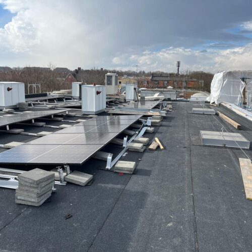 Solarmodule  werden  auf  einem  Flachdach  installiert,  während  der  Himmel  leicht  bewölkt  ist